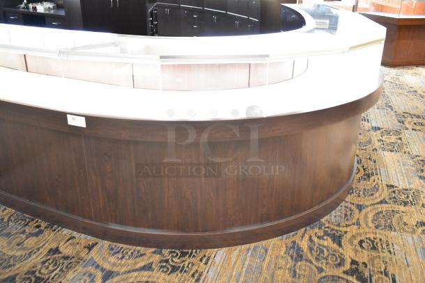 Curved wooden jewelry case with lighting, four rear doors, glass display top. Buyer to remove; bring tools and manpower.