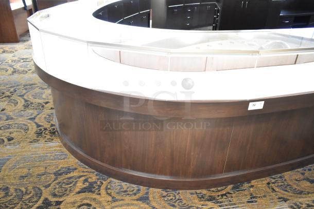 Curved wooden lighted jewelry case with glass top, 4 rear doors, good condition. Buyer must bring tools and manpower for removal.