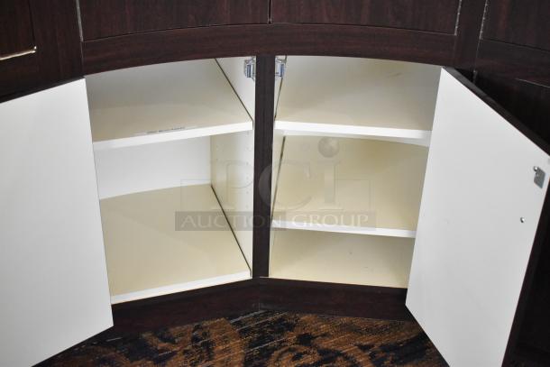 Wooden curved lighted jewelry case with 4 rear doors, dark finish, open doors reveal white shelving, used condition.