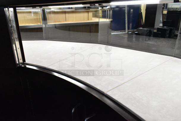 Wooden curved lighted jewelry case with glass top, four rear doors, and interior lighting. Condition appears good.