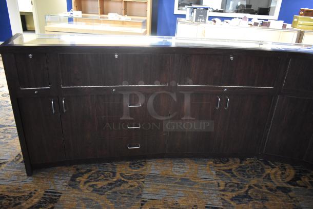 Wooden jewelry case with glass top, 4 rear doors, 3 drawers, and metal handles. Buyer must remove.