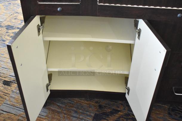 Wooden lighted jewelry case with open rear door, revealing interior shelves. Features three drawers. Good condition.