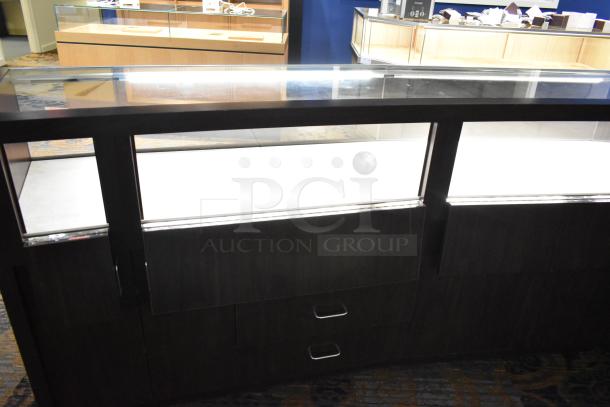 Wooden lighted jewelry case with 4 rear doors and 3 drawers, dark finish, glass top, good condition. Buyer to remove.