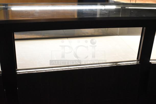 Wooden lighted jewelry case with 4 rear doors, 3 drawers; needs tools and manpower for removal.