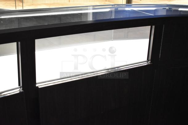 Wooden lighted jewelry case with four rear doors and three drawers. Requires tools and manpower for removal.