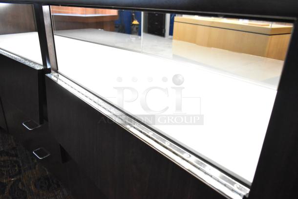 Wooden lighted jewelry case with 4 rear doors, 3 drawers; potential buyer must bring tools for removal.