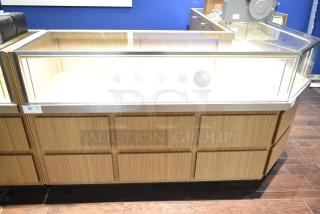 Wooden lighted jewelry case with glass top, four rear drawers, no key. Requires tools and manpower for removal.