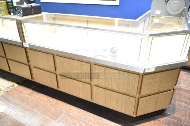 Wooden lighted jewelry case with glass top, four rear drawers, no key. Buyer must bring tools for removal.