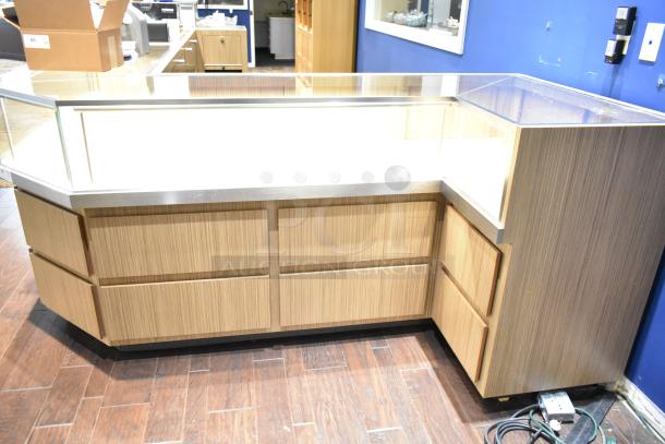 Wooden lighted jewelry case with 4 rear drawers, glass top, no key provided. Bring tools and manpower for removal.