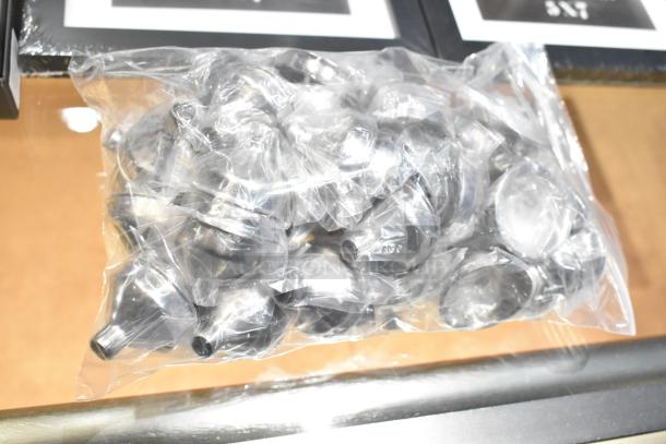 Bag of clear plastic funnels, bundled together. Distinct black and white frames visible in the background.