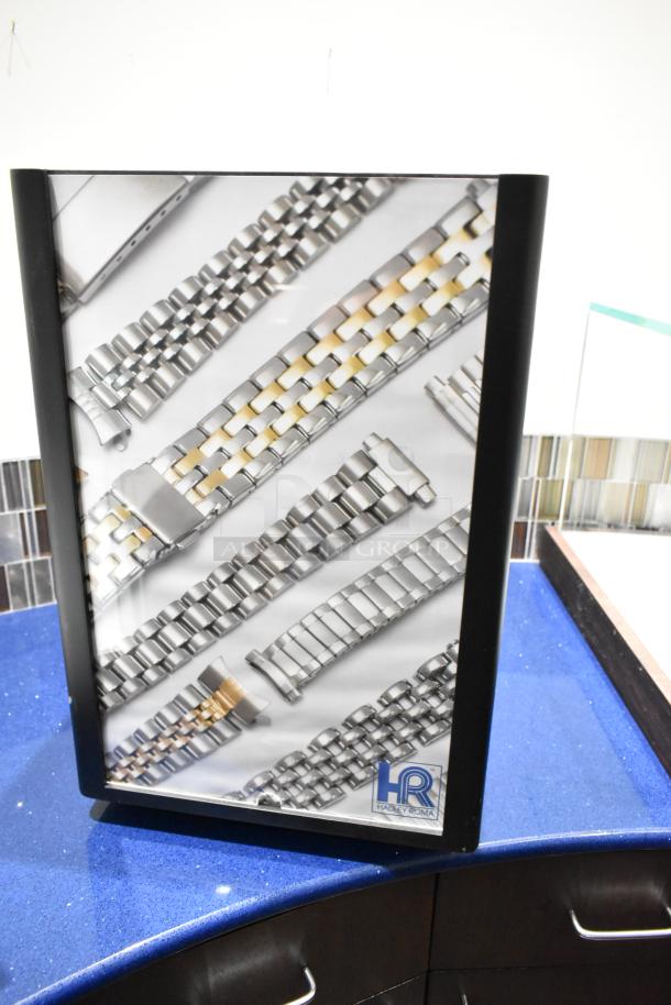 Hadley Roma display case with drawers, featuring various metal watchbands. Brand logo visible. Excellent condition.