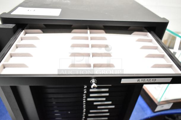 Hadley Roma case with multiple drawers, black finish, open drawer showing padded slots, visible label with numbers 8, 10, 12, 13.