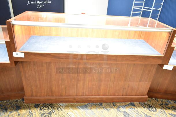 Wooden lighted jewelry case with two rear doors, three drawers, and glass top. Requires tools and manpower for removal.