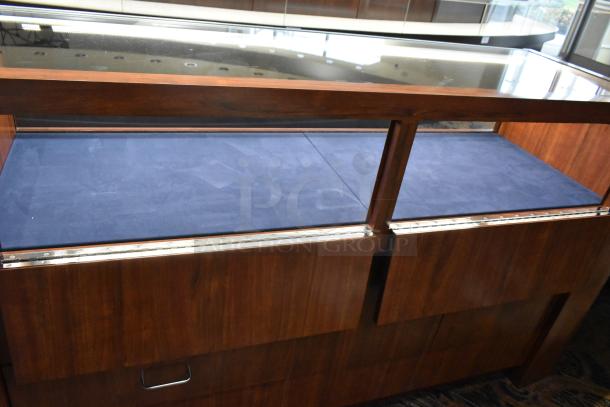 Wooden lighted jewelry case with glass top, 2 rear doors, 3 drawers, blue interior, needs tools for removal.