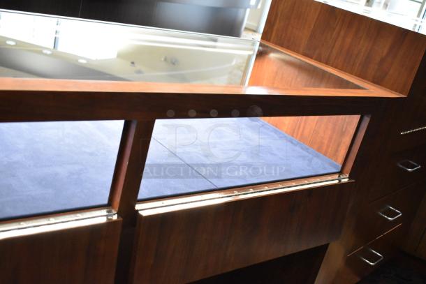 Wooden lighted jewelry case with glass display, rich finish, and blue interior. Good condition. Buyer must remove.