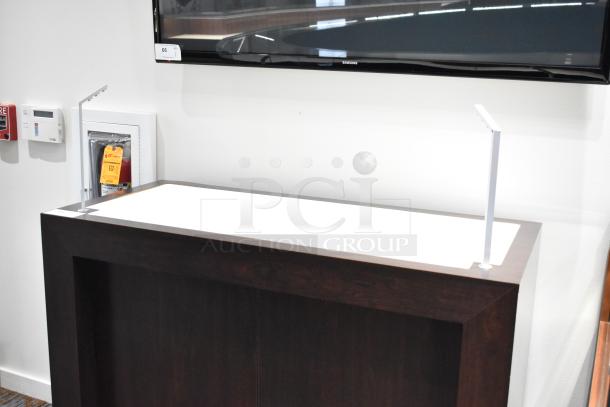 Dark wooden desk with minimalist design, featuring a rectangular shape and smooth finish; appears in good condition.