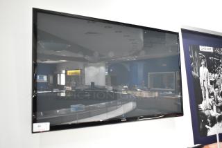 Samsung Television mounted on a wall, large screen, glossy finish, in-store setting. Buyer must remove.