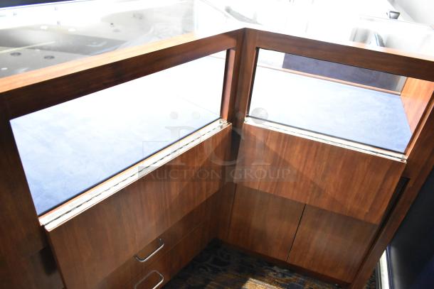 Wooden corner lighted jewelry case with glass top, two rear doors, and three drawers. Buyer needs tools to remove.