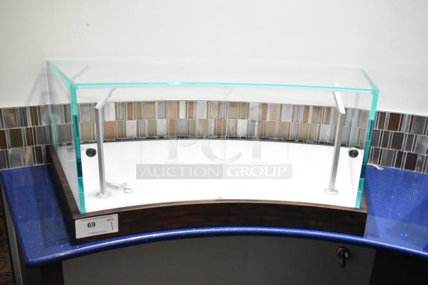 Curved glass countertop display case with metal supports, in excellent condition, features key lock and wooden base.