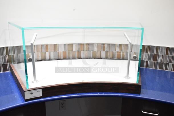 Curved glass countertop display case with metal supports and wooden base, in excellent condition. Auction tag reads "70 QTY 1".