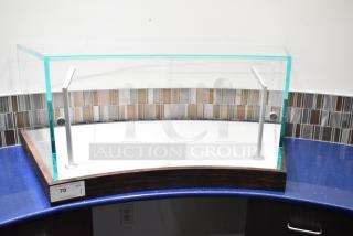 Curved glass countertop display case with metal supports and wooden base, in excellent condition. Auction tag reads "70 QTY 1".