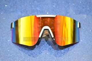 Brand new golden framed sunglasses with orange lens, reflecting a rainbow hue, set on a textured blue surface.