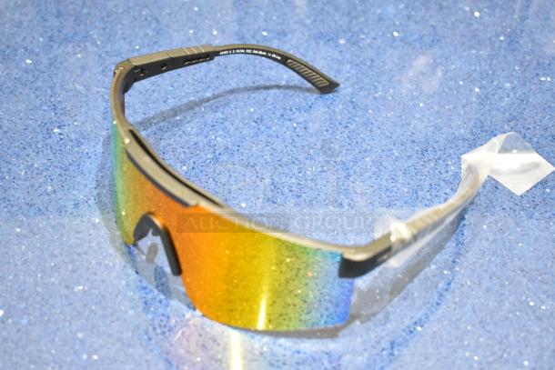 Brand new golden framed sunglasses with vibrant orange lenses, featuring sleek design and protective wrapping.