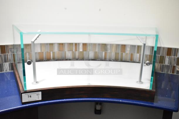 Curved glass countertop display case with metal supports, in excellent condition. Tag reads "74, QTY 1, PCI Auctions."