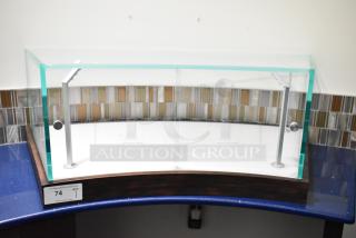 Curved glass countertop display case with metal supports, in excellent condition. Tag reads "74, QTY 1, PCI Auctions."