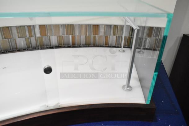 Curved glass countertop display case with metal supports, white base, and mosaic tiled back. In excellent condition.