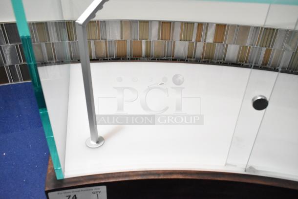 Clear glass countertop display case with metal frame, chrome accents, curved design, and wooden base. Good condition.