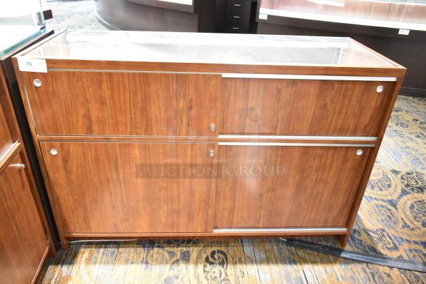 Wooden lighted jewelry case with glass top, metal trim, and lockable doors. Good condition. Buyer must remove.