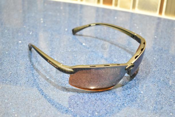 Brand new brown framed sunglasses with BluBlocker brown lenses on a blue surface.