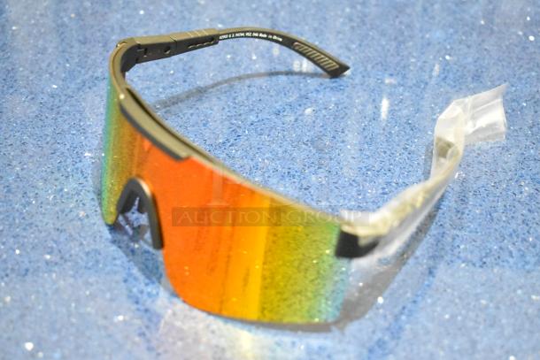 Brand new tan framed sunglasses with orange lens on blue surface; protective plastic on arms; U.S. patent marking visible.