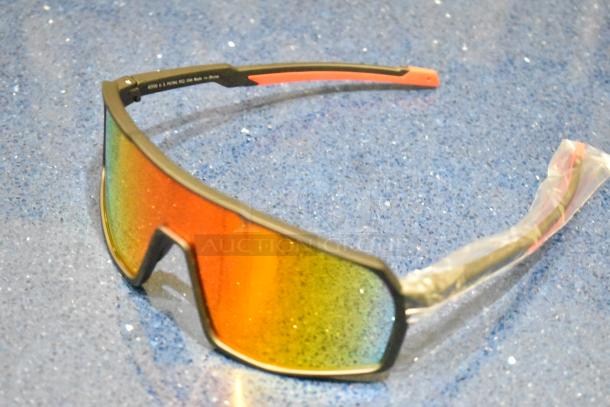 Brand new tan framed sunglasses with vibrant orange lenses; features a sleek, modern design; protective arm wrap intact.