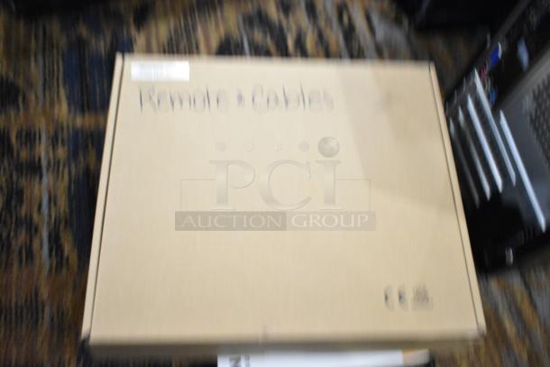 Cardboard box labeled "Remotes & Cables," likely containing tech items like an Insignia landline phone cord and HDMI cable.