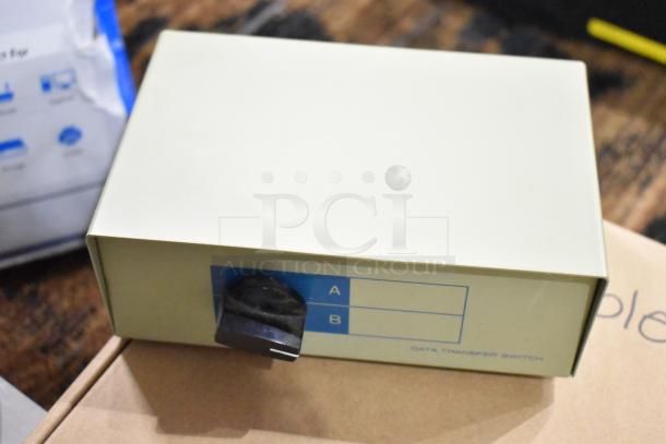 Gray data transfer switch box with A/B toggle, labeled "DATA TRANSFER SWITCH." Used condition on a brown surface.