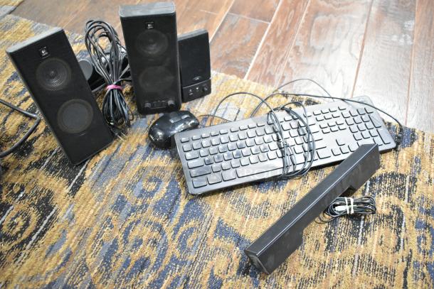 Collection of 6 tech items including Logitech speakers, computer keyboard, mice, and cables on patterned rug.