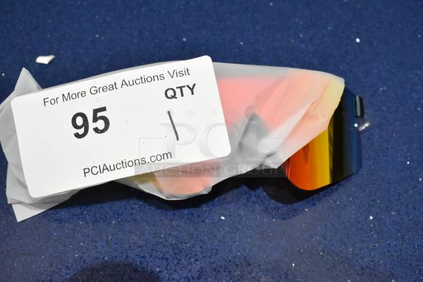 Brand new golden framed sunglasses with orange lens, partially wrapped, auction tag showing "95" and "PCIauctions.com".