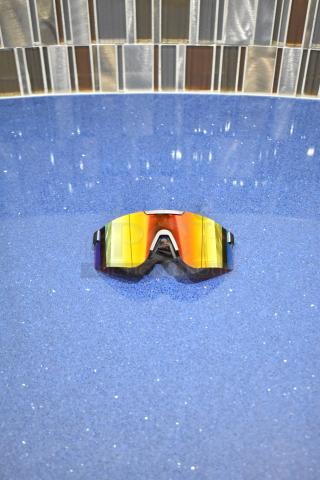 BRAND NEW gray framed sunglasses with reflective BluBlocker orange lenses on blue surface.