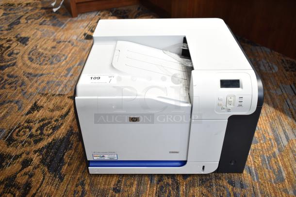 HP Color LaserJet CP3525x printer in good condition, features control panel, model label, placed on patterned carpet.