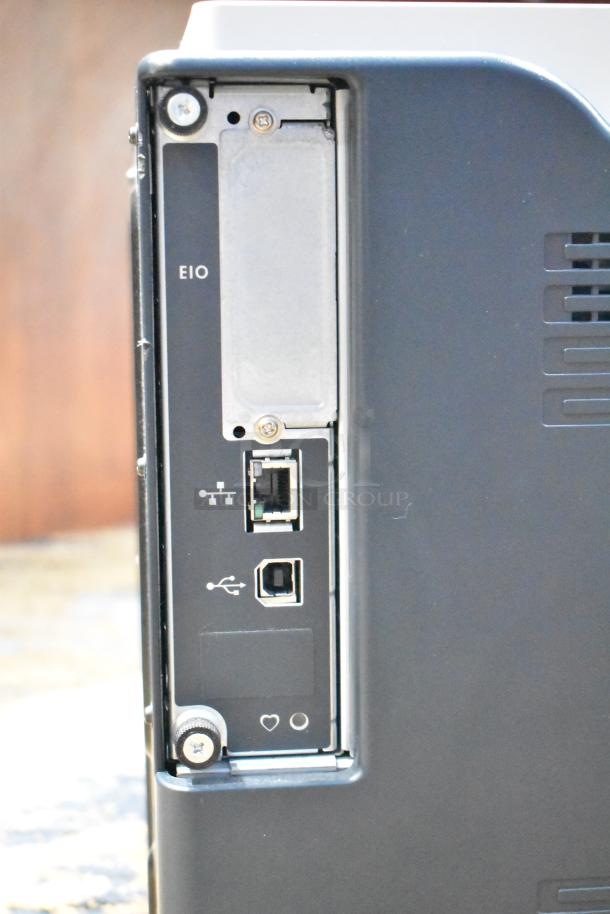 HP Color LaserJet CP3525x printer showing back panel with EIO, network, and USB ports.