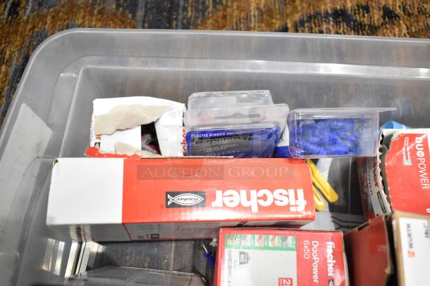 A plastic bin containing assorted hardware items, including Wurth screws, Fischer DuoPower wall anchors, and various packaging. Condition appears used.
