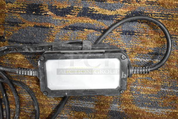 Husky string lights on a patterned carpet, featuring a rugged black casing and visible power cords, in used condition.