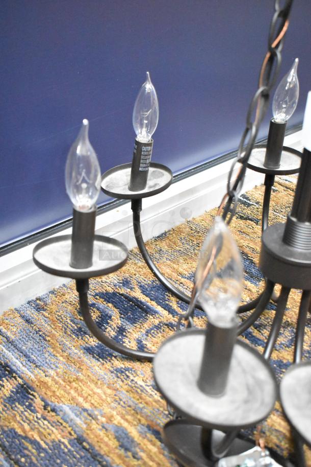 Black finish chandelier with candle-style light fixtures. Elegant design, good condition, chain-link detail, suitable for dining.