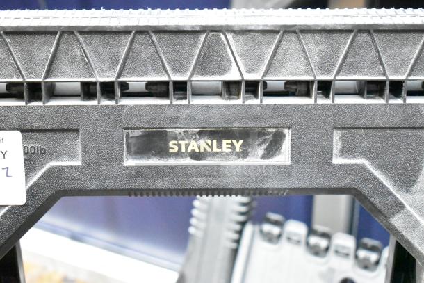 2 Stanley black poly sawhorses, sturdy design, visible brand logo, suitable for heavy-duty tasks.