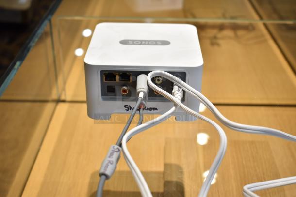 Sonos Connect streaming device with multiple ports, visible wires, and "Showroom" label; used for stereo updates.