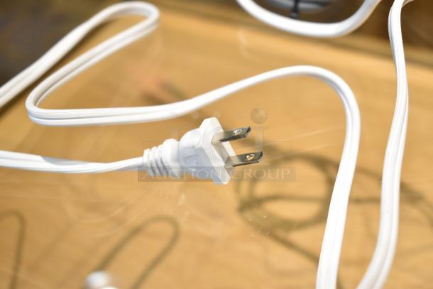 Close-up of a white power cord plug on a reflective surface, potentially for a Sonos Connect streaming device.