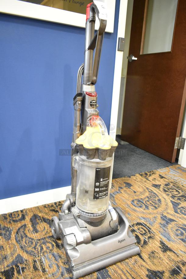 Dyson DC33 Vacuum Cleaner, upright model in used condition, 115 volts, 1 phase, visible dust bin, and attachment tools.