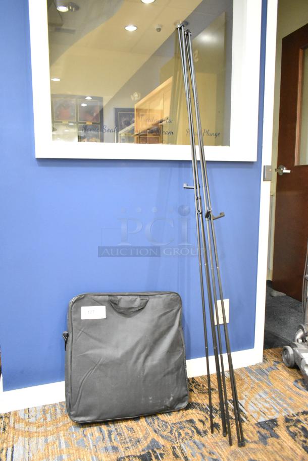 Set of three black metal frames with foldable legs and a black carrying bag, all in good condition. Bag labeled "127."